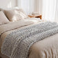 Plaid grosse maille gris sur lit